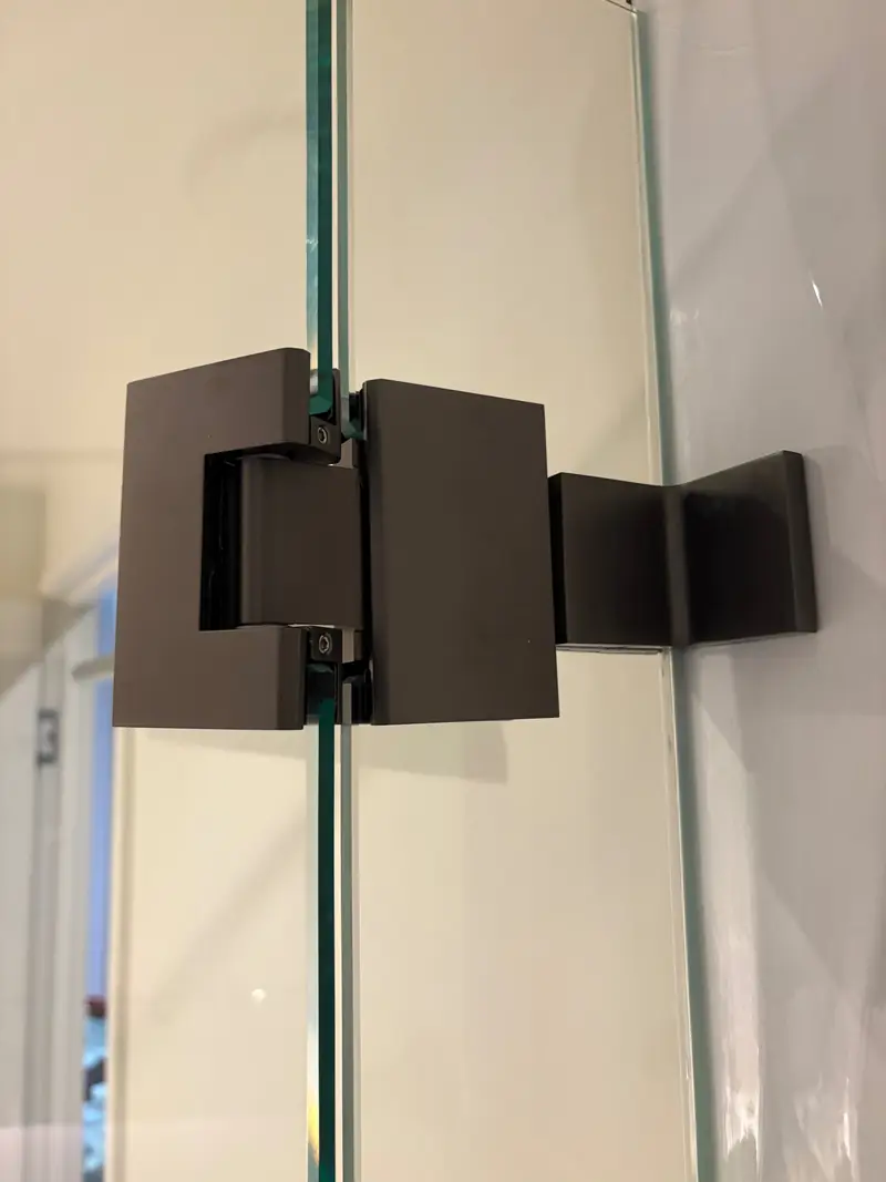 Black glass-to-wall shower screen hinge detail