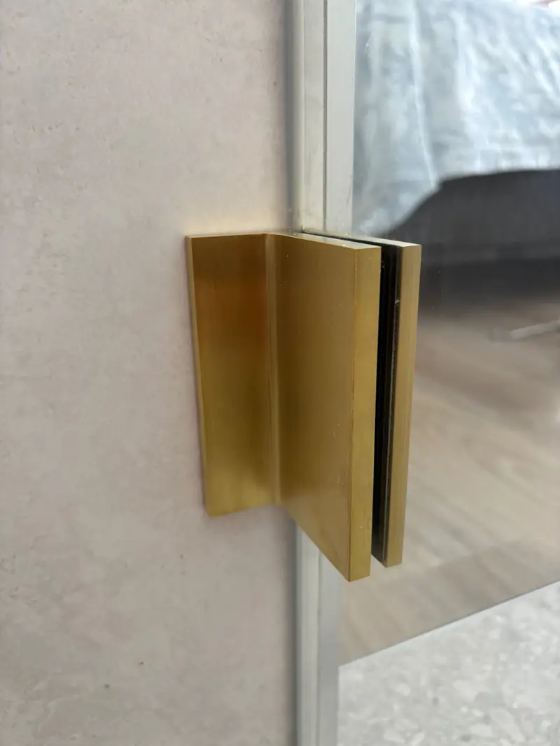 Brushed brass shower screen hinge close-up