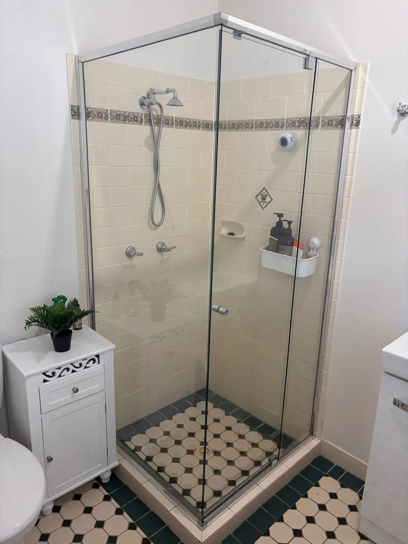 Chrome semi-frameless corner shower over a mosaic tile floor