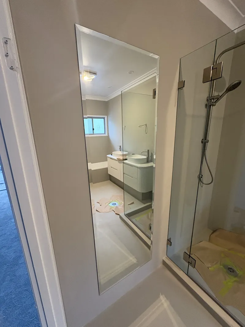 Tall custom bevelled-edge wall mirror installed beside a frameless shower in a Brisbane bathroom