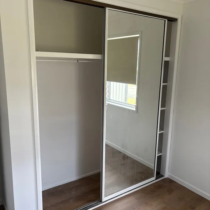 White-framed sliding wardrobe doors with mirror panel, installed by Elder Glass in Brisbane