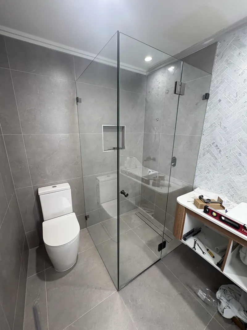 Frameless corner shower screen with black hardware and grey tiles, Brisbane