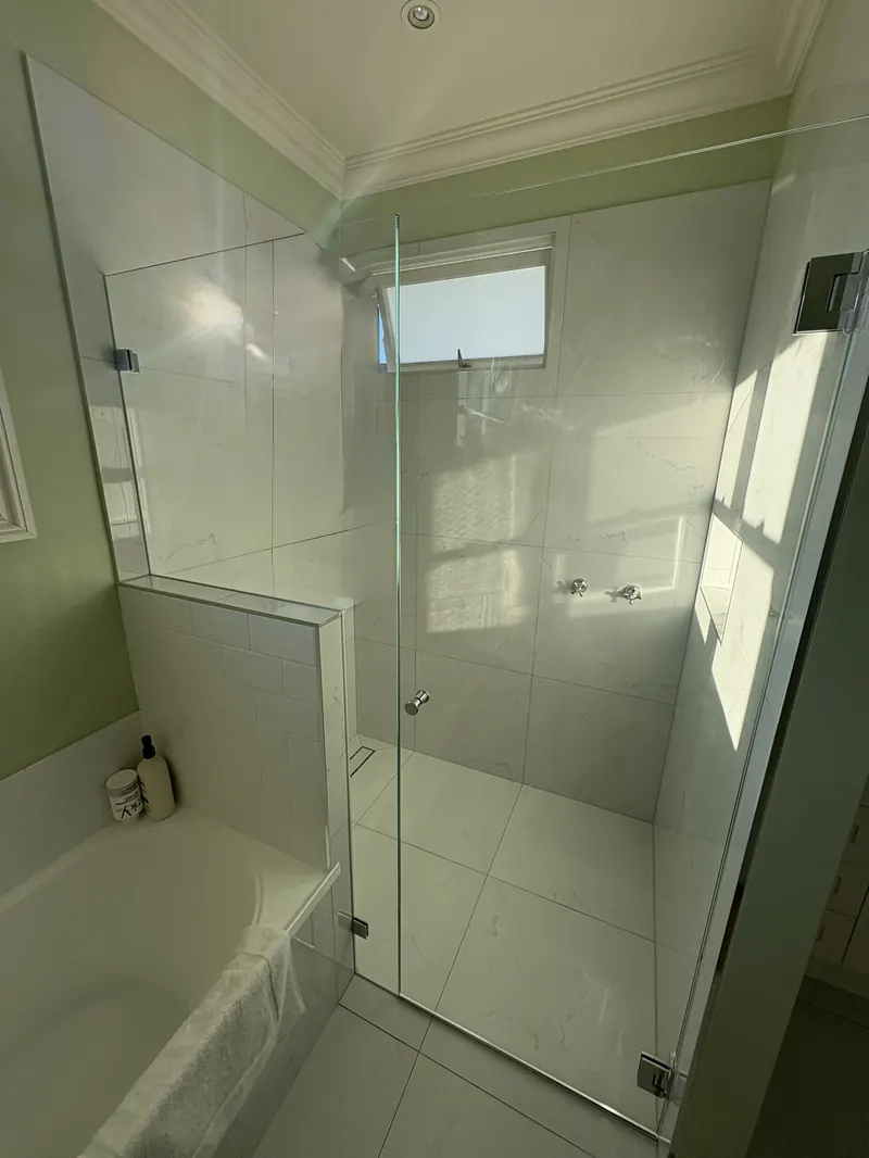Frameless shower door and fixed panel beside a bath, installed by Elder Glass in Brisbane