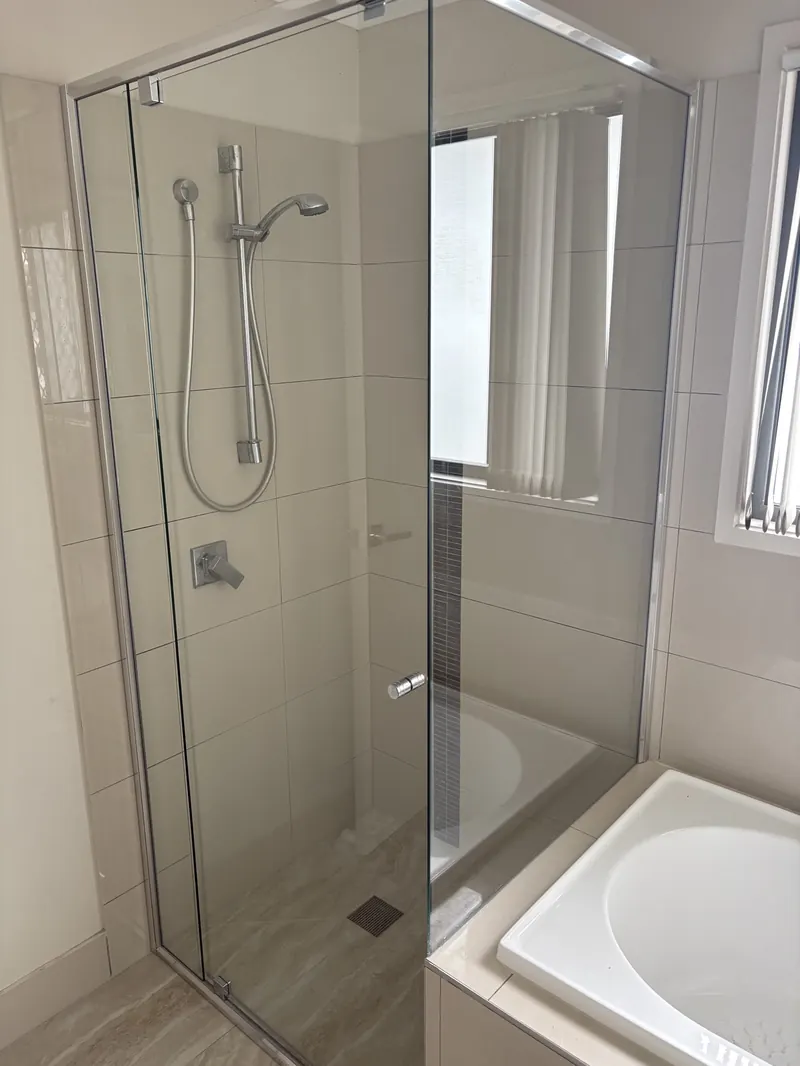 Frameless glass shower panel under a window in a Brisbane bathroom renovation