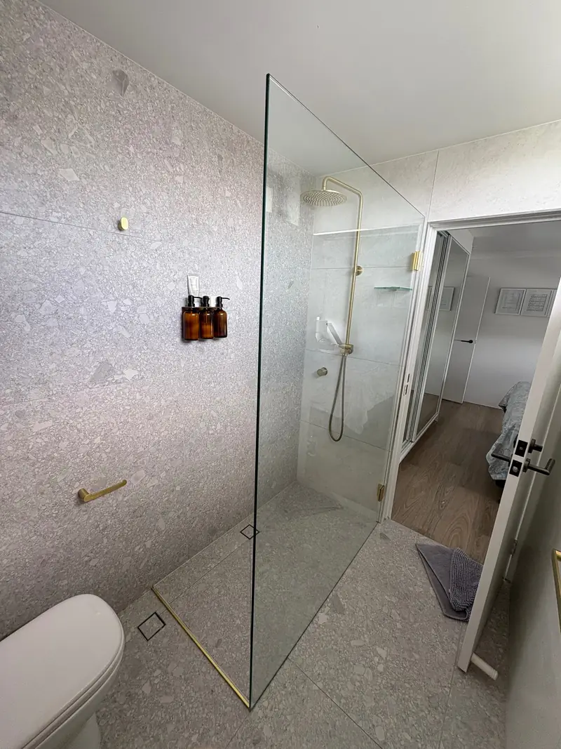 Frameless shower screen in a stone-tiled bathroom