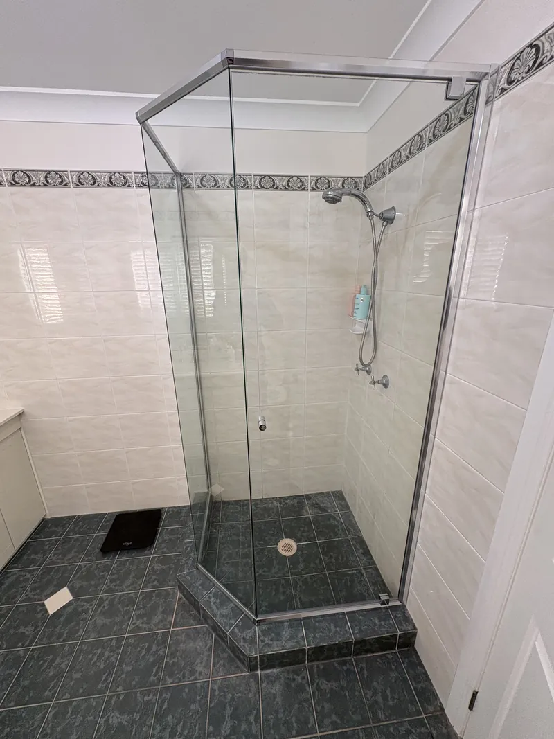 Semi-frameless angled corner shower on a tiled hob with chrome frame, Brisbane