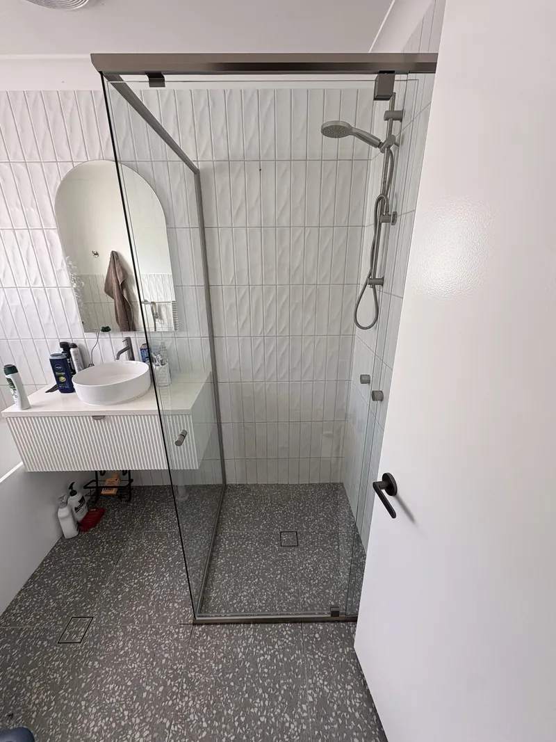 Semi-frameless corner shower with brushed nickel frame, white vertical tiles and terrazzo floor, Brisbane