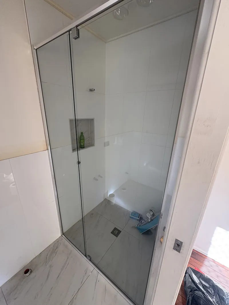 Semi-frameless shower screen with door and chrome frame beside a tiled niche, Brisbane