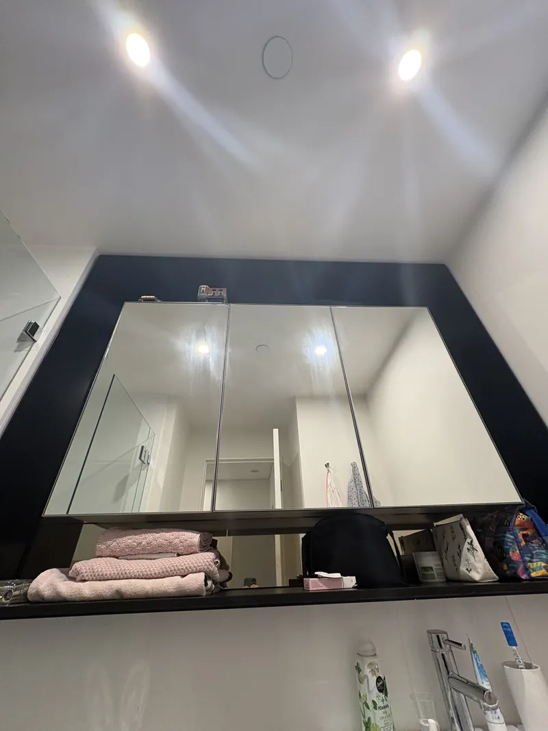 Three-door mirrored shaving cabinet mounted on a dark feature panel, Brisbane