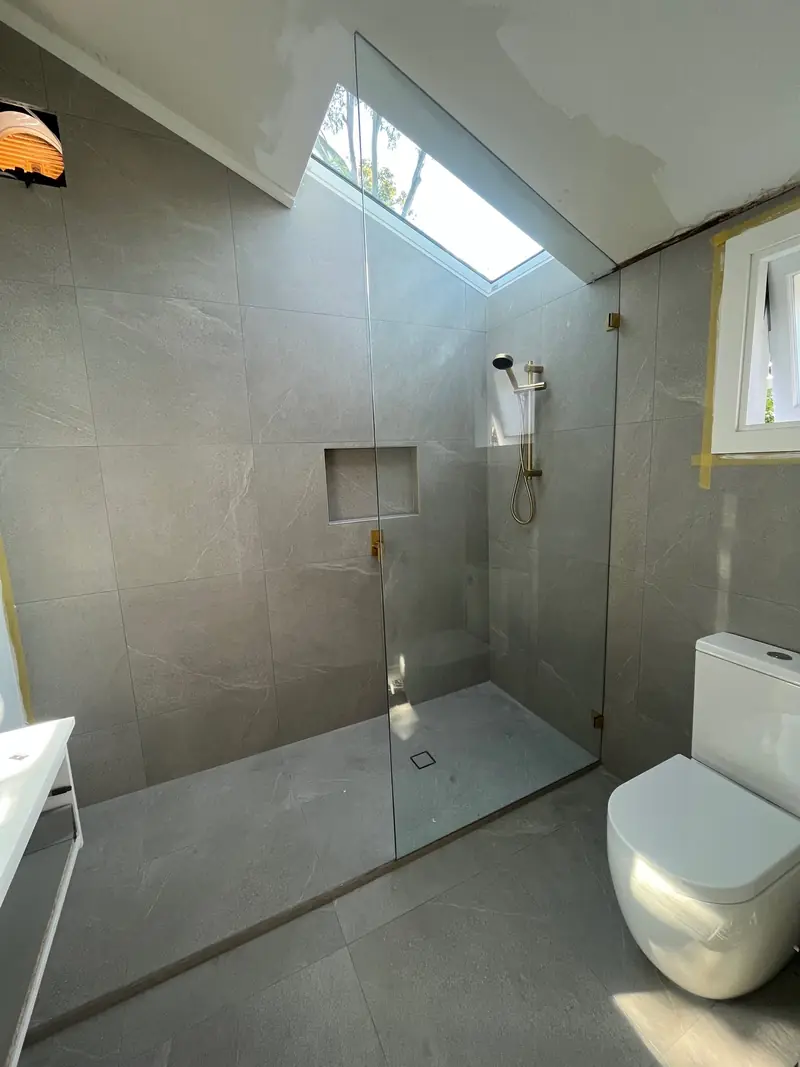 Walk-in frameless shower panel under a skylight