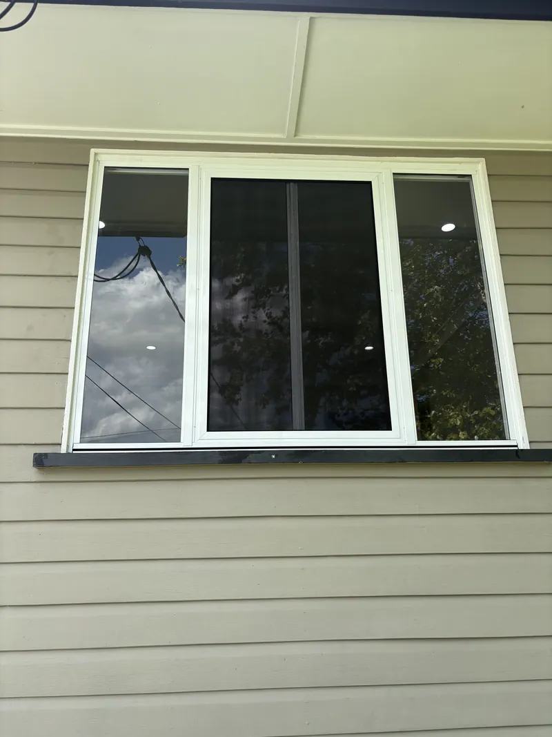 White aluminium three-panel sliding window on a weatherboard home, Brisbane