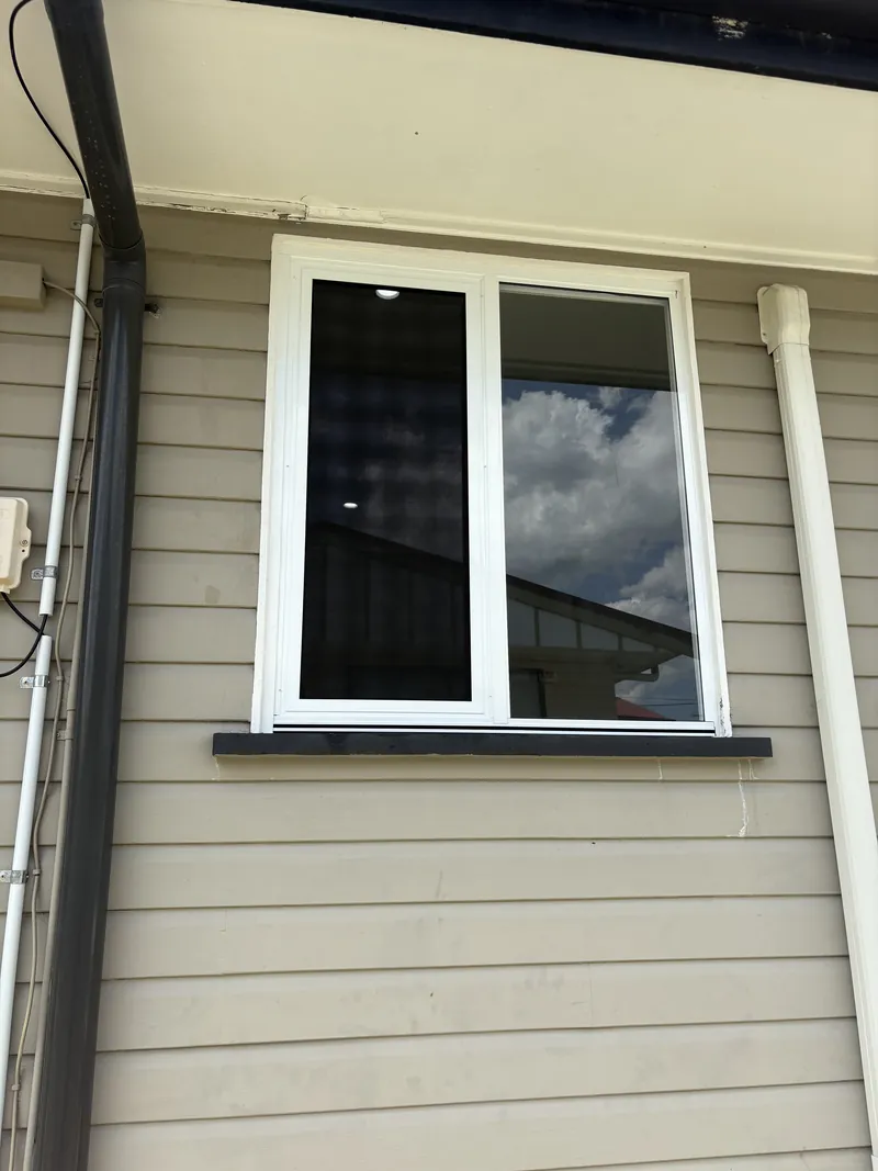 White aluminium two-panel sliding window installed in a weatherboard wall, Brisbane