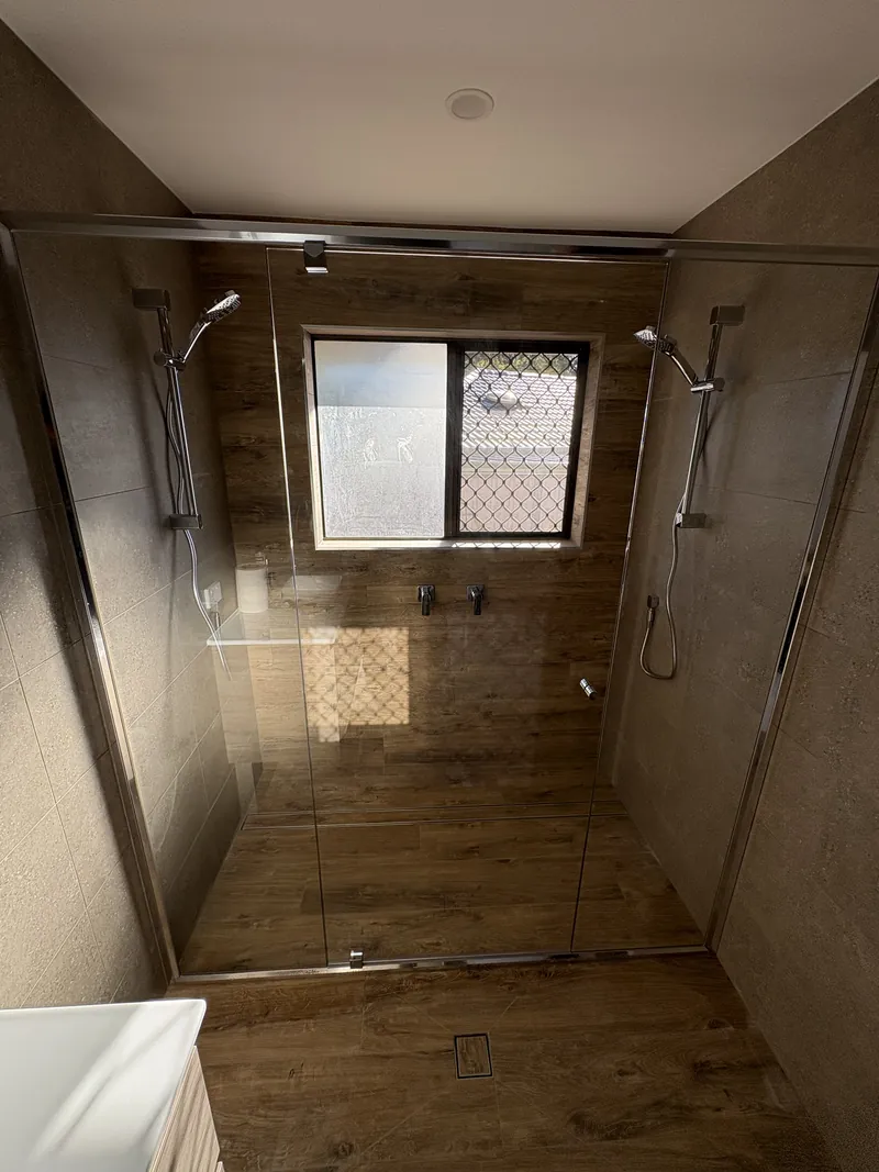 Wide semi-frameless shower screen with chrome frame and double shower in timber-look tiles, Brisbane